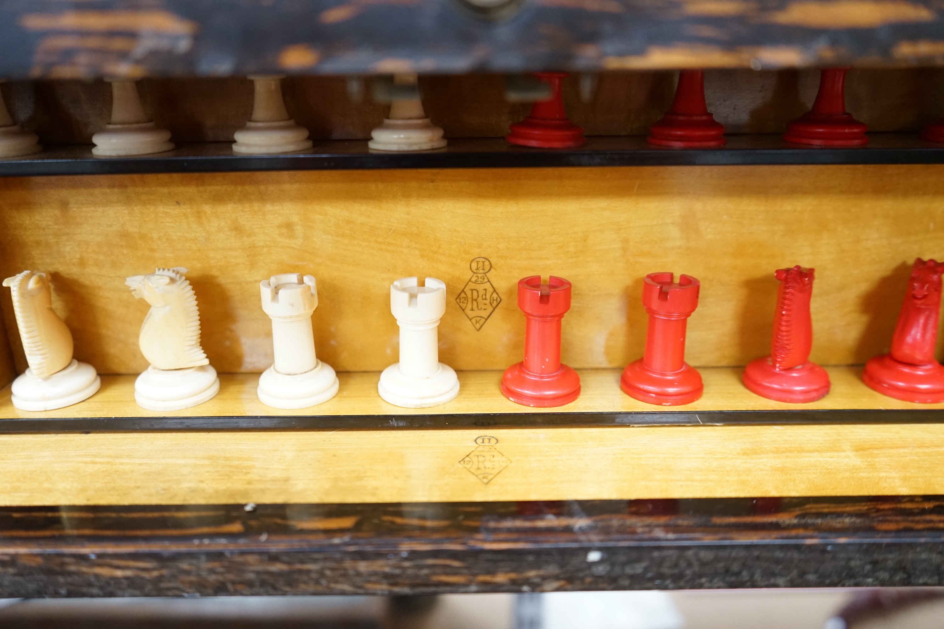 A Victorian coromandel games box with accessories, ivory chess pieces and counters, box 36cm wide x 19cm high. Condition - red interior leather worn and torn in places and box scratched, minor losses to chess pieces. CIT